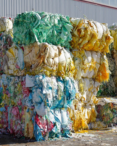 Stacks of multicoloured wool bales in front of a building,ready to be recycled into melton clothing 